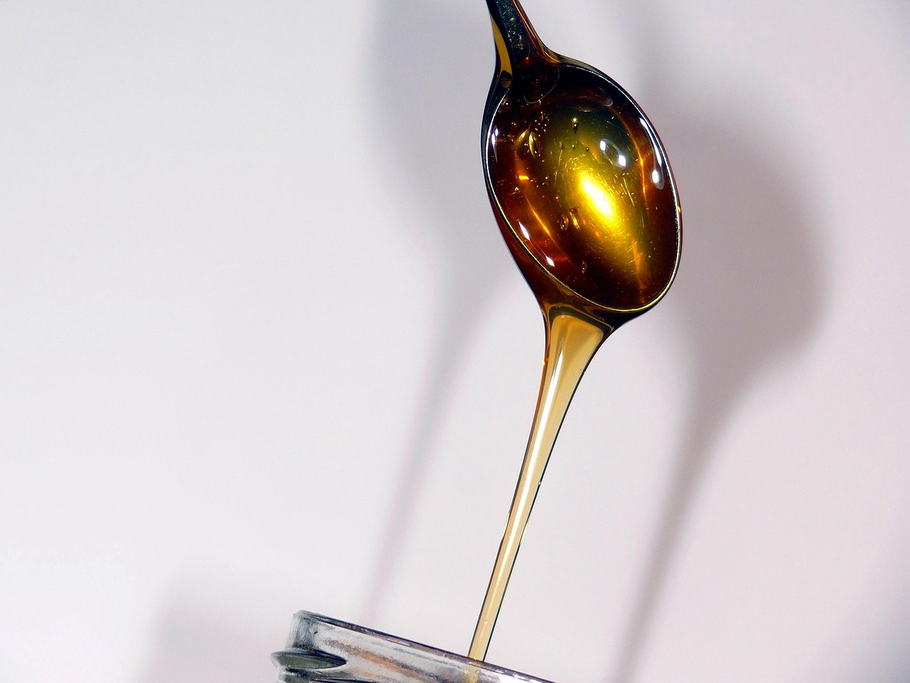 Miele che cola da un cucchiaio, rimedio naturale per la gola